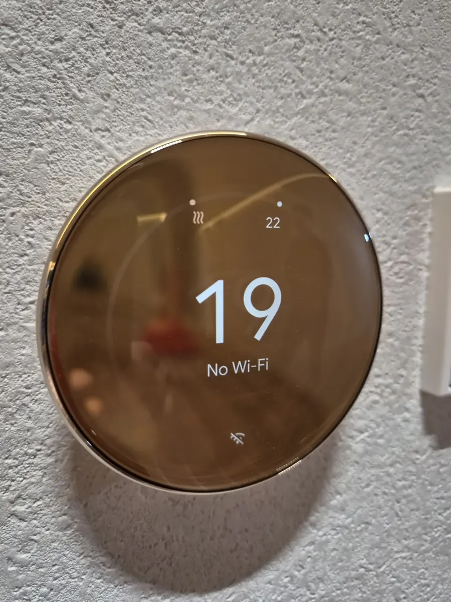 금색 링 마감 구글네스트 온도조절기 근접 사진, 화면에 19도와 No Wi-Fi 표시